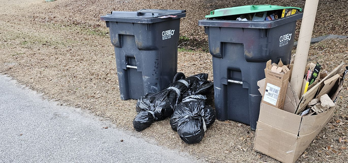 Next to the trash cans: black wrapped shapes that look suspiciously like human forms. 