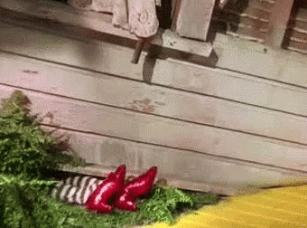 Scene from the Wizard of Oz where the wicked witch's feet curl up beneath Dorothy's fallen house.
